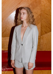 Woman wearing a Lvory Leather Blazer Coat against a wooden wall.