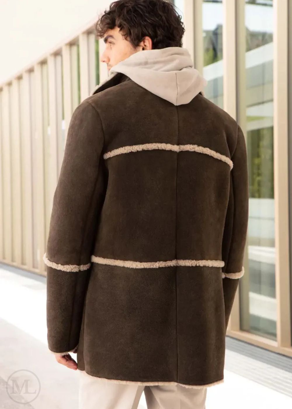 Men wearing a brown suede shearling coat with beige trim in an indoor setting.