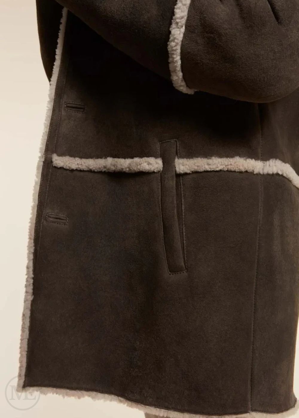 Close-up of a brown suede coat with light brown trim on a beige background