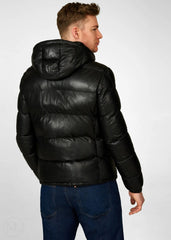 Man wearing a black leather puffer jacket on a white background