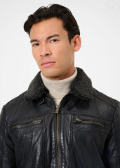Man wearing a black leather jacket with a fur-lined collar on a white background