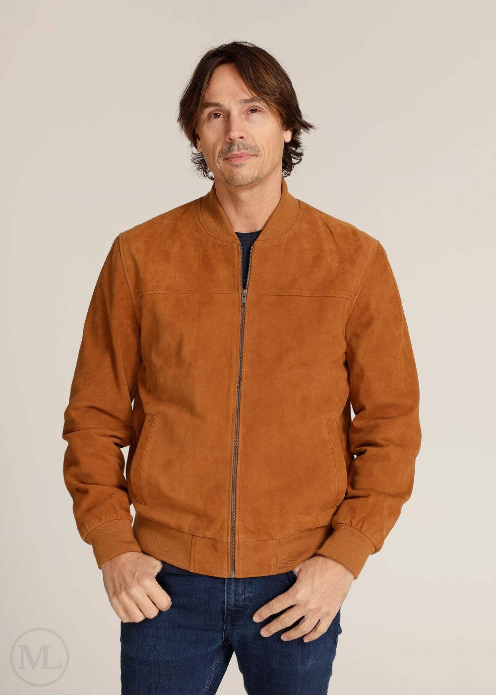 Man wearing a cognac brown suede jacket against a beige background