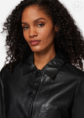 Woman wearing a black leather cropped jacket against a white background