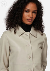 Woman wearing a lvory leather cropped jacket coat with a plain background
