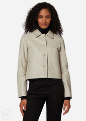 Woman wearing a lvory cropped jacket over a black outfit on a white background