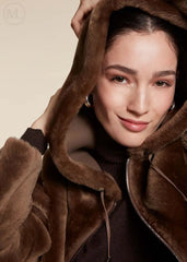 Woman wearing a brown shearling wool coat against a beige background