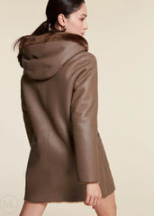 Brown leather shearling wool coat with fur hood worn by a woman on a beige background