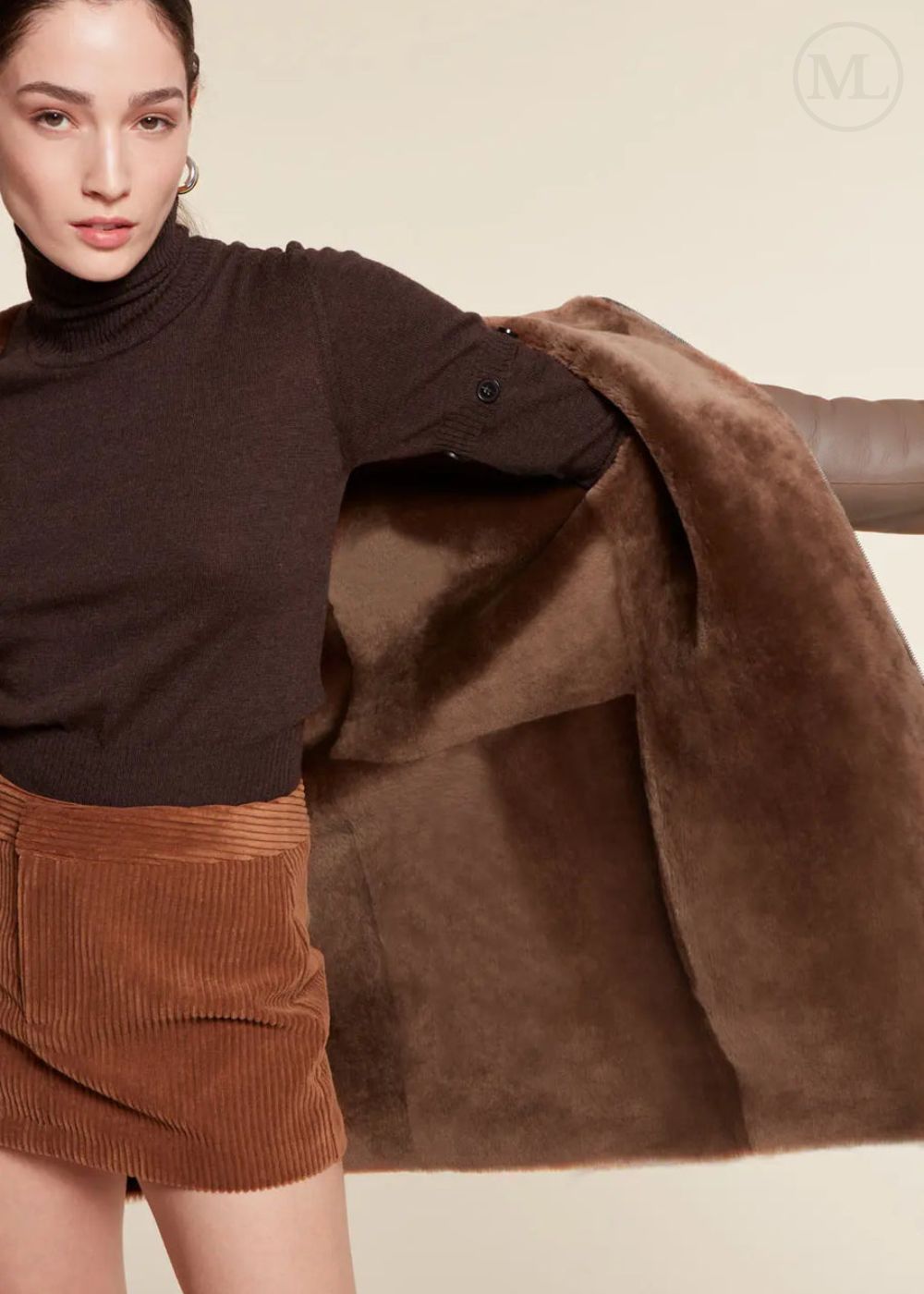 Woman wearing a brown shearling wool coat and corduroy skirt