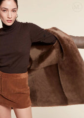 Woman wearing a brown shearling wool coat and corduroy skirt