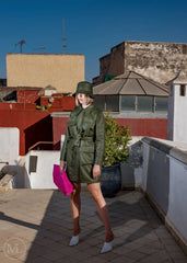 Woman wearing a Olive green outfit standing on a rooftop with buildings in the background