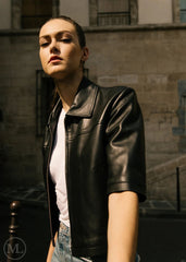 Women wearing a cropped black leather shirt-jacket in an urban setting