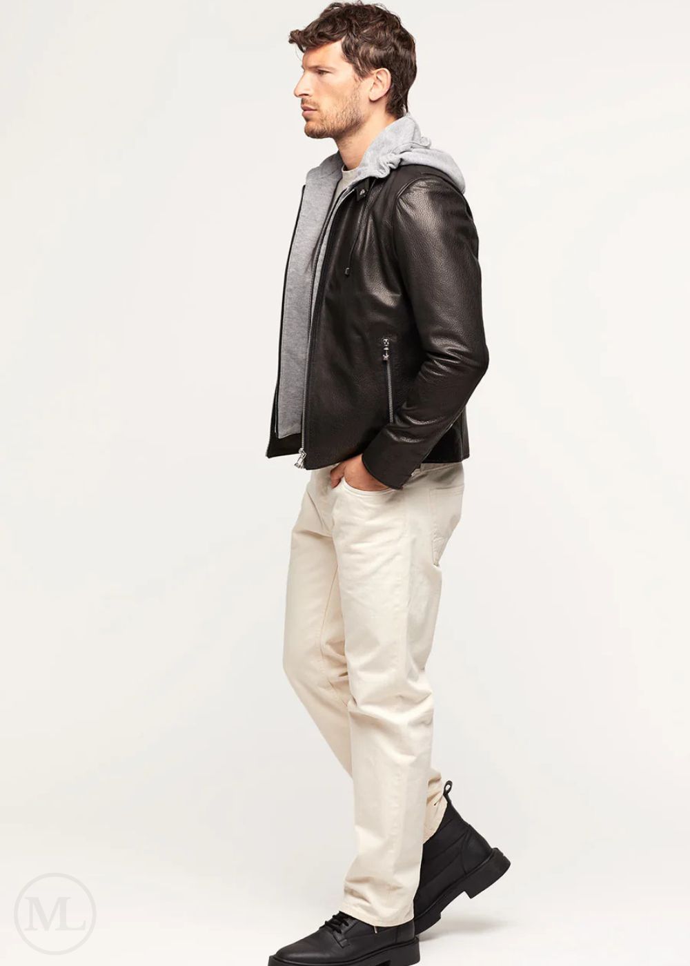 Man wearing a black lambskin leather jacket and white pants on a white background