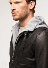 Man wearing a black leather jacket with a gray hood on a light gray background - close view