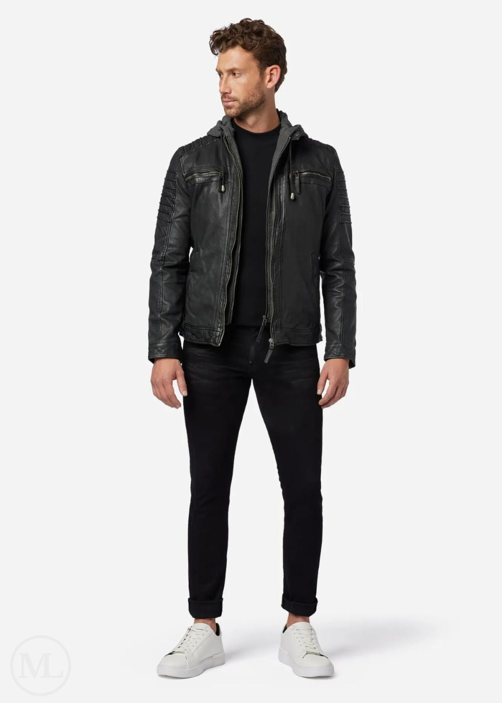 Man wearing a black leather jacket, black pants, and white shoes on a white background