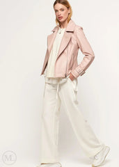 Woman wearing a fuschia leather biker jacket over a white outfit on a white background