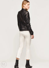 Woman wearing a black leather biker jacket and white pants on a white background