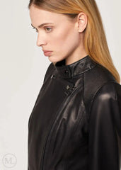 Woman wearing a black leather biker jacket on a plain background