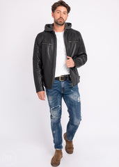Man wearing a black leather Motorcycle jacket, white shirt, blue jeans, and brown boots on a white background
