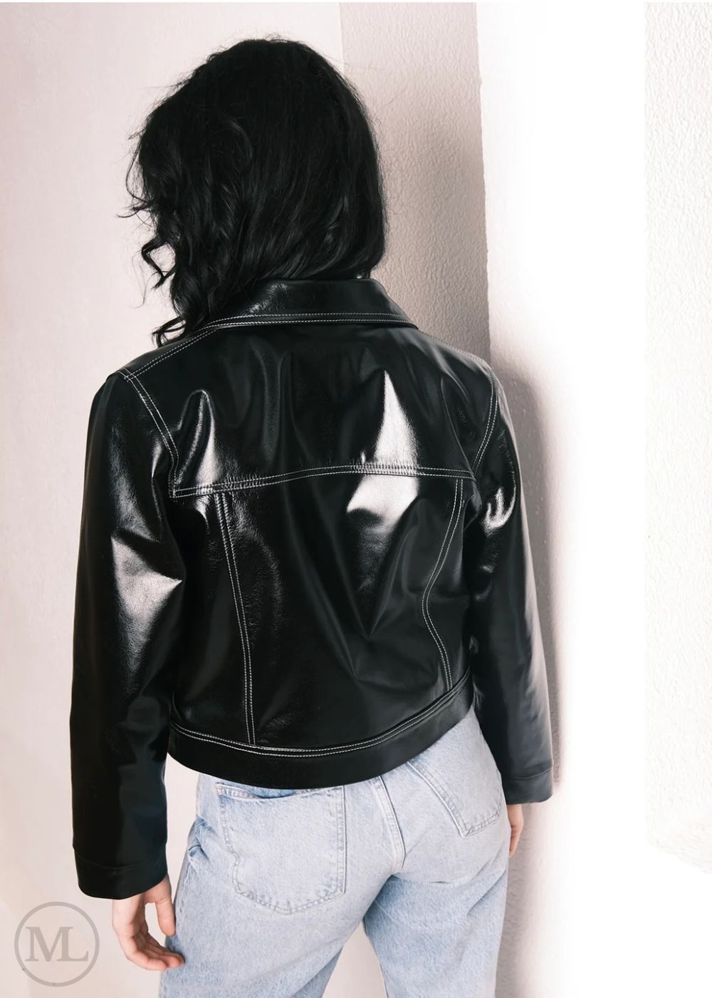 Women wearing a Cropped black leather Trucker jacket and light blue jeans against a neutral background