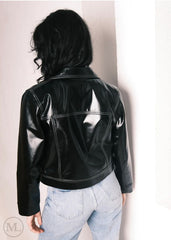Women wearing a Cropped black leather Trucker jacket and light blue jeans against a neutral background