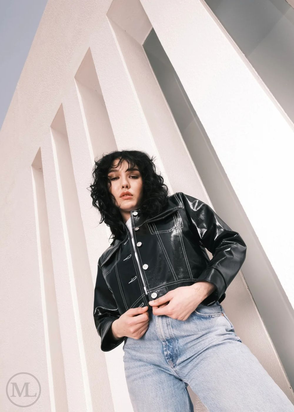 Women wearing a Cropped black leather Trucker jacket and light blue jeans against a neutral background
