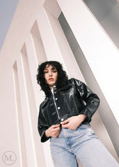 Women wearing a Cropped black leather Trucker jacket and light blue jeans against a neutral background