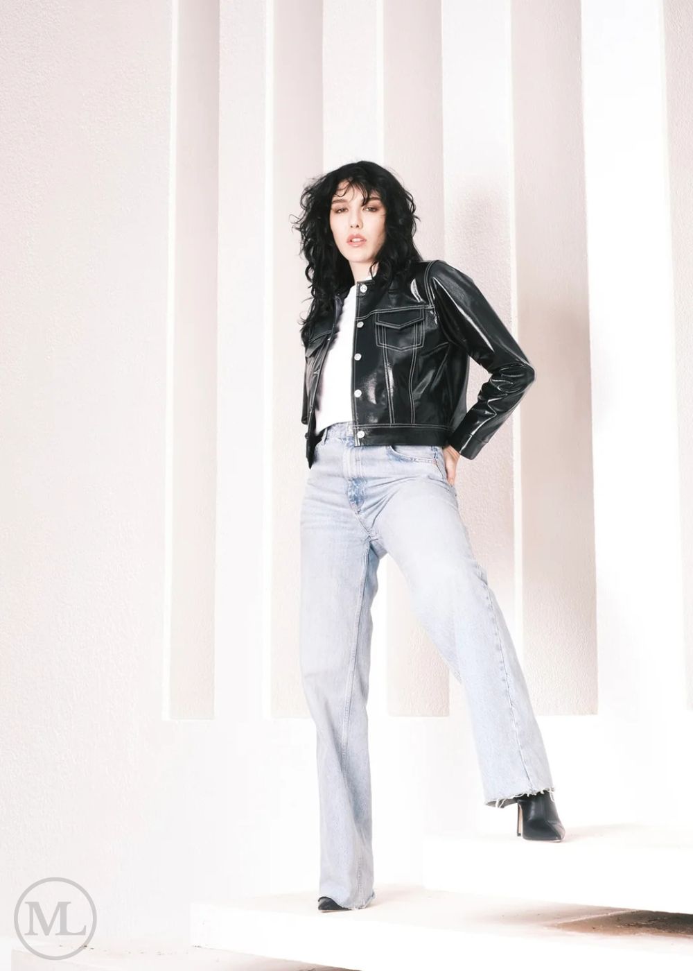 Women wearing a Cropped black leather Trucker jacket and light blue jeans against a neutral background