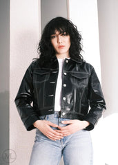 Women wearing a Cropped black leather Trucker jacket and light blue jeans against a neutral background