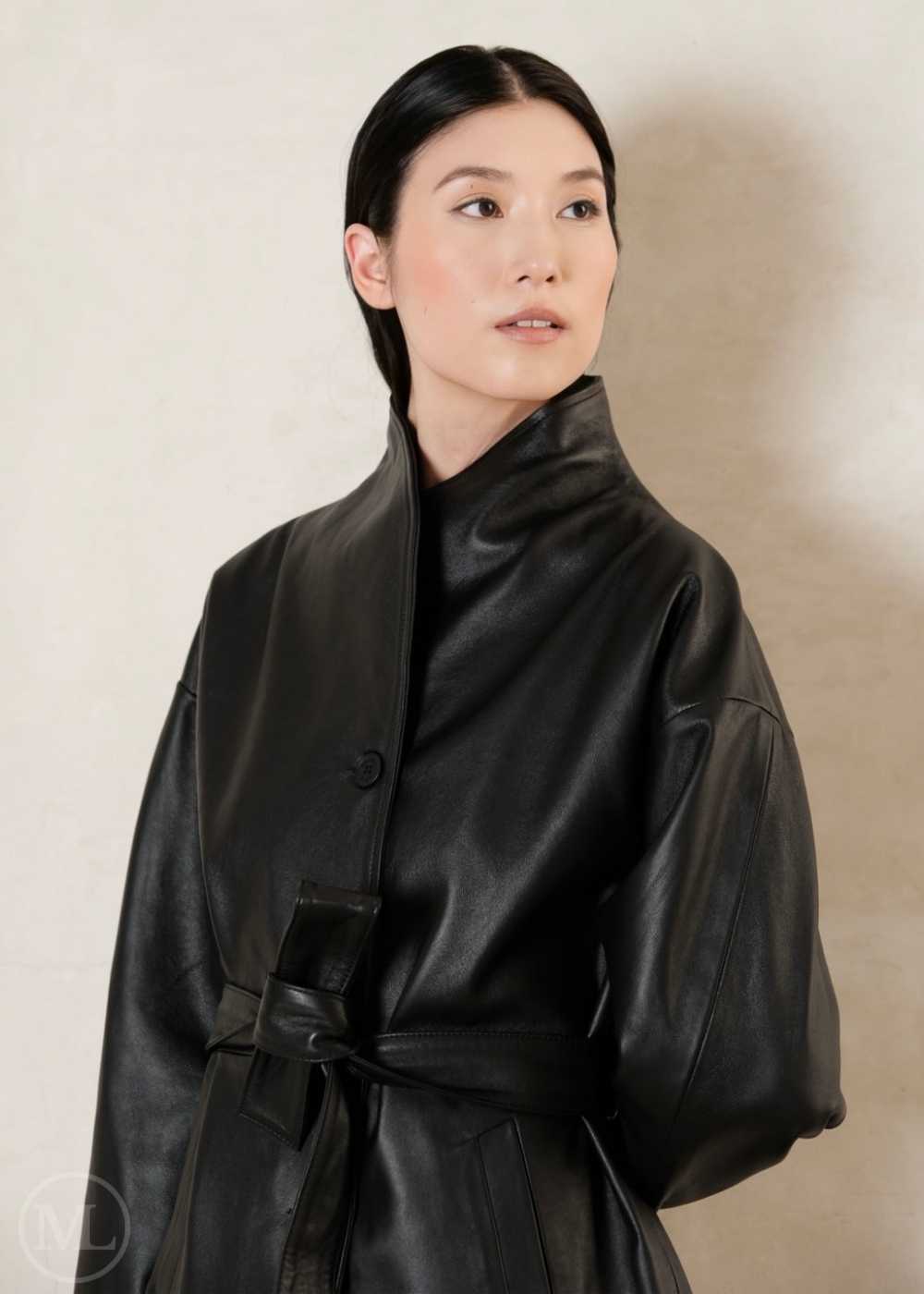 Woman wearing a black leather coat against a plain background