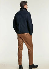 Man wearing a navy blue jacket and brown pants on a white background