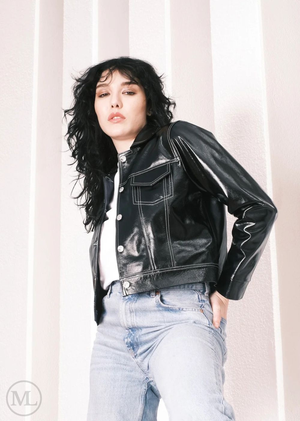 Woman wearing a black leather jacket and light blue jeans against a neutral background
