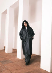 Women wearing a  Long Leather Trench Coat standing in a minimalist setting with white columns.
