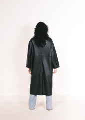 Women wearing a  Long Leather Trench Coat standing in a minimalist setting with white columns.