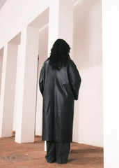 Women wearing a  Long Leather Trench Coat standing in a minimalist setting with white columns.