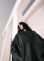 Women wearing a  Long Leather Trench Coat standing in a minimalist setting with white columns.