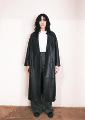 Women wearing a  Long Leather Trench Coat standing in a minimalist setting with white columns.
