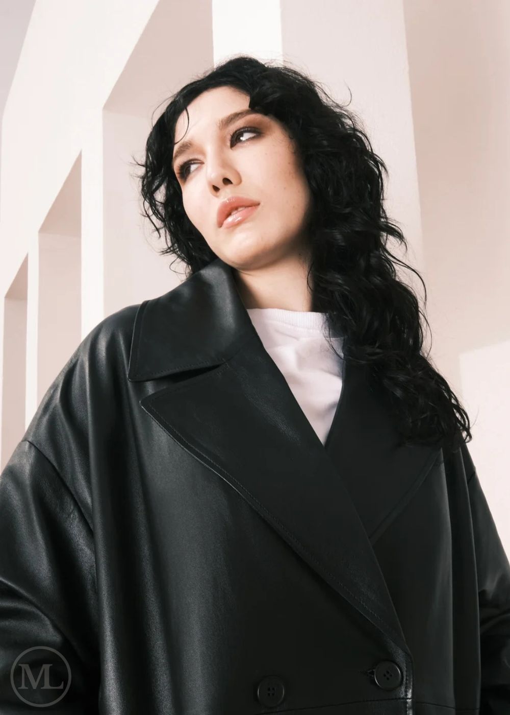 Women wearing a  Long Leather Trench Coat standing in a minimalist setting with white columns.