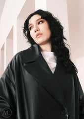 Women wearing a  Long Leather Trench Coat standing in a minimalist setting with white columns.