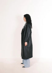 Women wearing a  Long Leather Trench Coat standing in a minimalist setting with white columns.