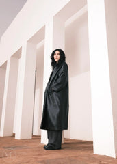 Women wearing a  Long Leather Trench Coat standing in a minimalist setting with white columns.