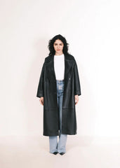 Women wearing a  Long Leather Trench Coat standing in a minimalist setting with white columns.