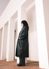 Women wearing a  Long Leather Trench Coat standing in a minimalist setting with white columns.