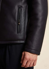 Close-up of a dark blue leather jacket with a zipper worn by a man on a beige background