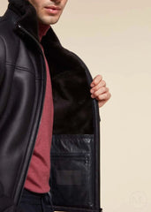 Man wearing a dark blue leather jacket with a visible brand logo on a beige background