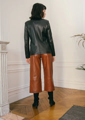 Women wearing a black leather Blazer jacket and orange pants standing on a city street