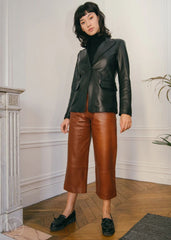 Women wearing a black leather Blazer jacket and orange pants standing on a city street