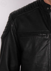 Close-up of a black leather jacket with quilted shoulder design worn by a man on a white background