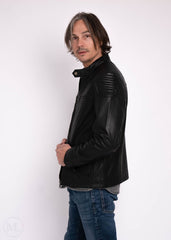 Man wearing a black leather jacket and blue jeans on a white background