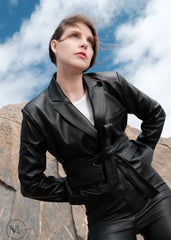 Woman wearing a black leather Blazer Coat outfit standing against rocky terrain with blue sky.