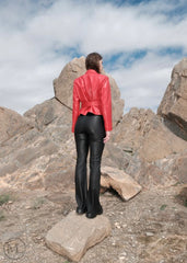 Woman wearing a red Leather Blazer jacket and black pants standing on rocky terrain with a blue sky.